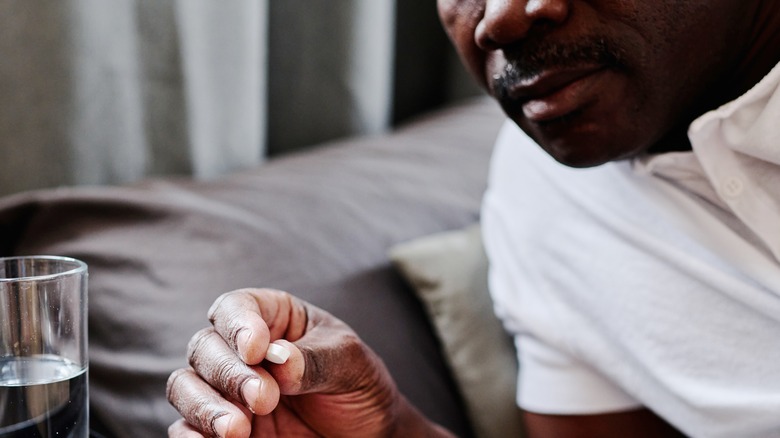 man getting ready to take pill while in bedroom