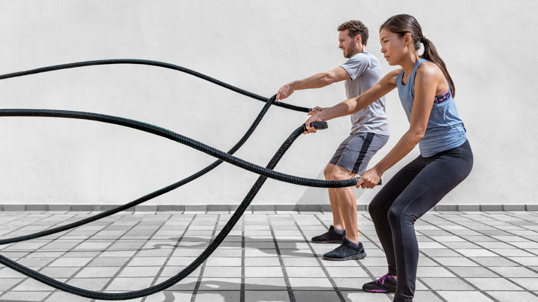 Man and woman whipping battle ropes