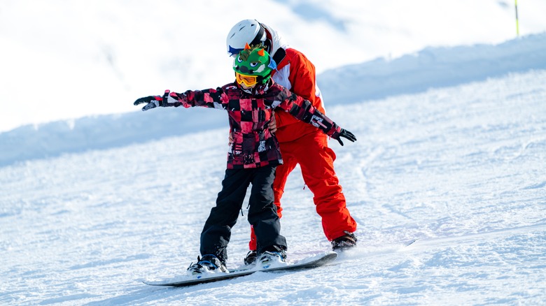 Child receiving snowboard lessons
