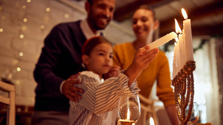 Family lighting Hanukkah candles