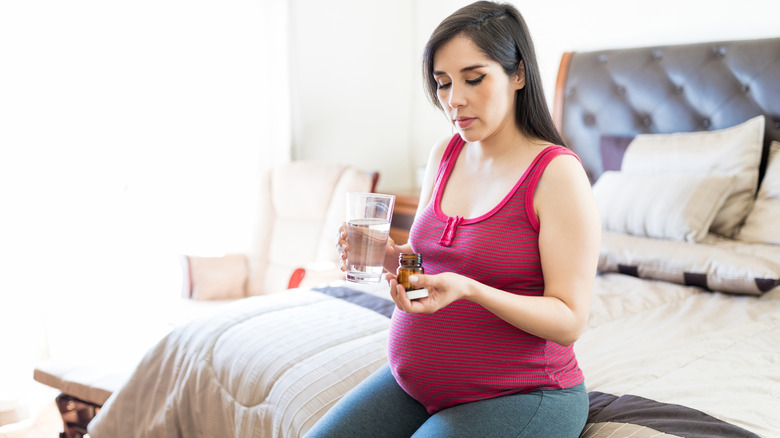 Pregnant woman holding vitamin bottle