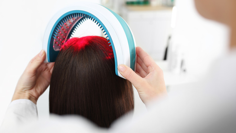 Woman having laser device put on her head