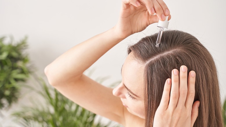 woman applying essential oil to scalp