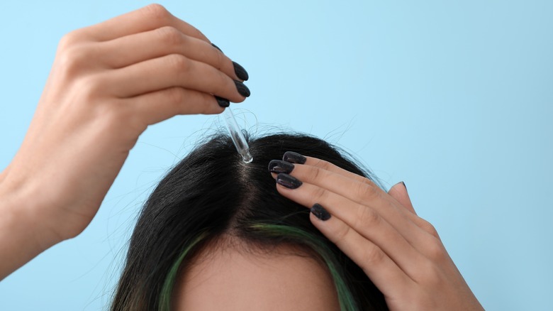woman using serum in dropper for hair loss