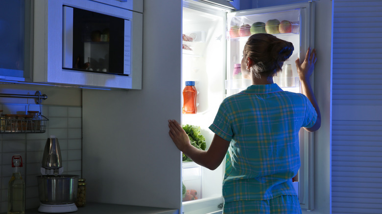 woman looking in refrigerator at night