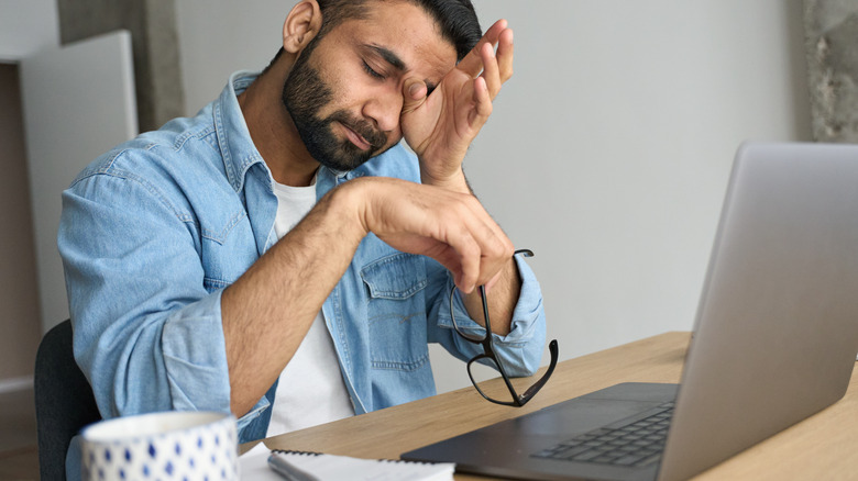 man rubbing eyes while working