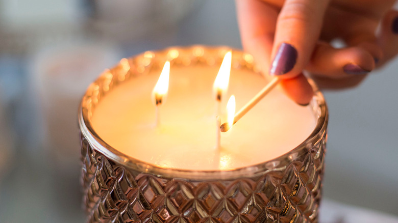 person with painted nails lighting candle