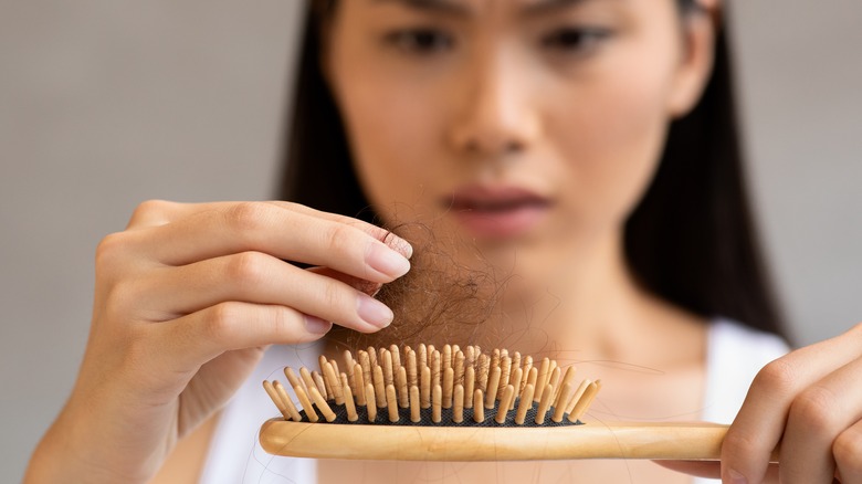 a woman pulling out hair from her brush 