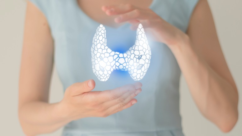 concept image of woman holding thyroid hologram