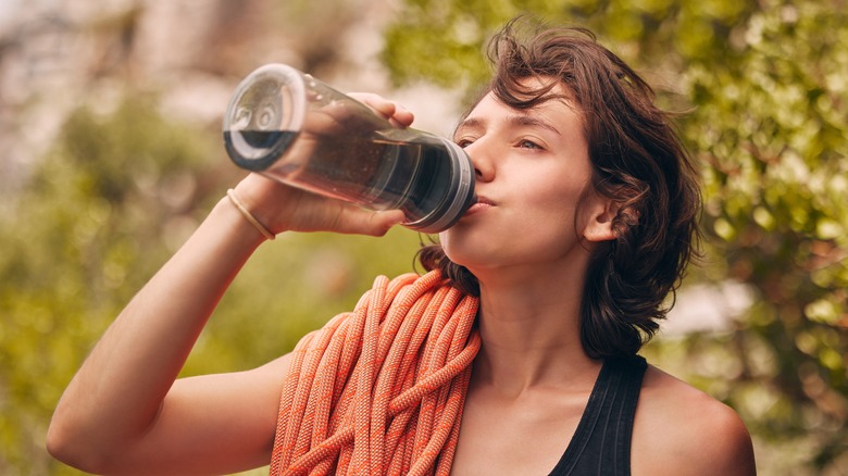 Rock climbing woman drinking water