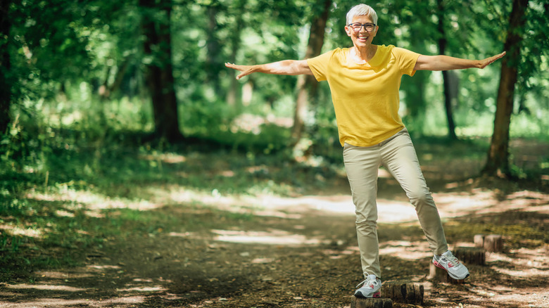 older woman balancing on one leg in a park