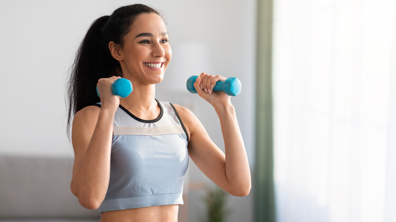 Fit woman lifting weights at home