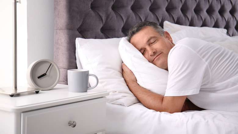 older man sleeping on stomach hugging pillow