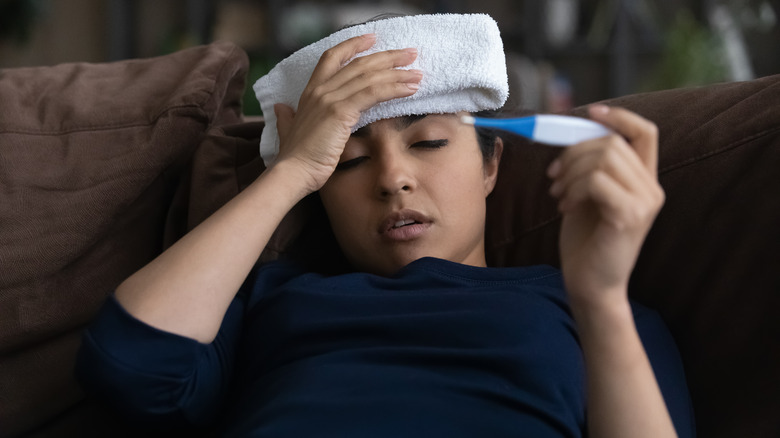 woman with towel to head looking at thermometer