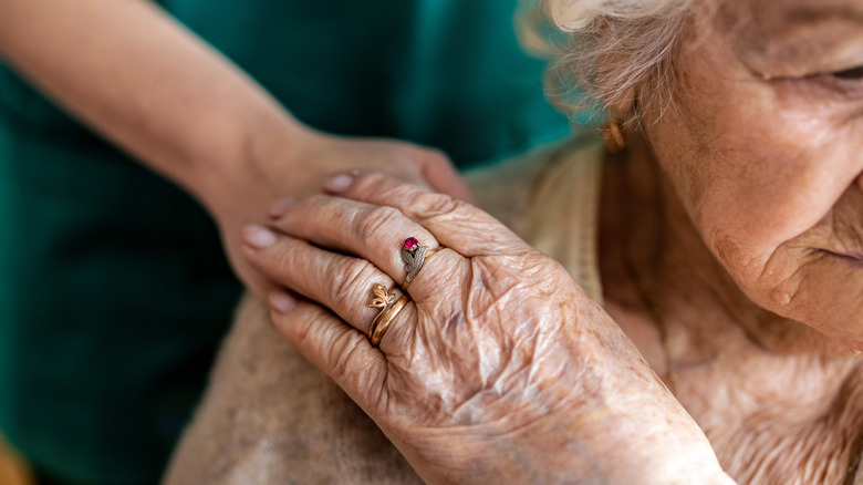 A senior woman holding hands with a nurse