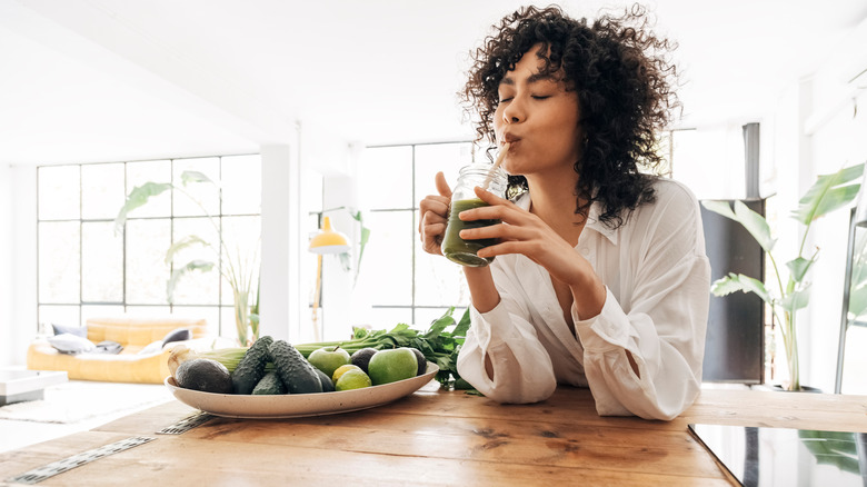 A woman drinks a green smoothie