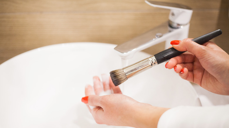 woman washing makeup brush 