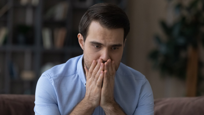 worried man sitting down with his hands covering his mouth