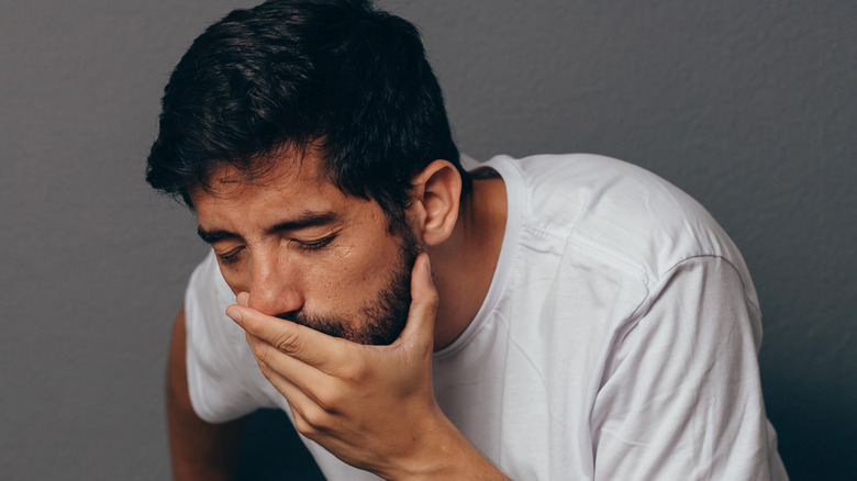 Nauseous man holding mouth