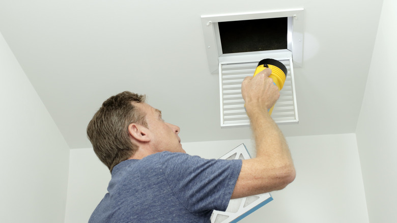 Man inspecting air conditioning vent