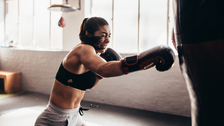 A woman hitting a punching bag in a gym