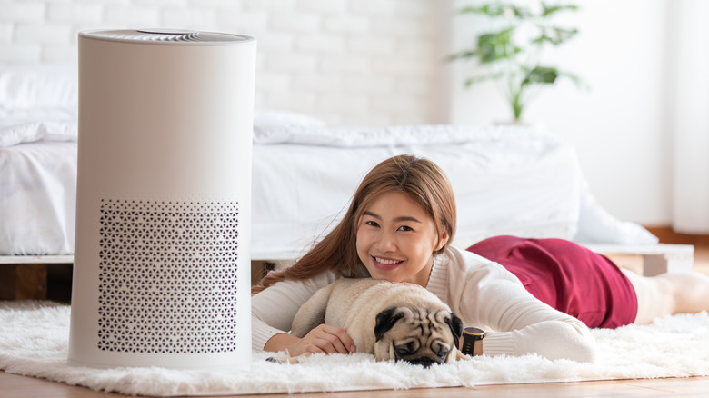 Smiling young woman cuddling pug 