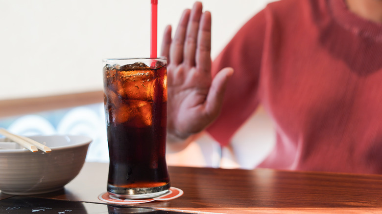 Woman saying no to a glass of soda 