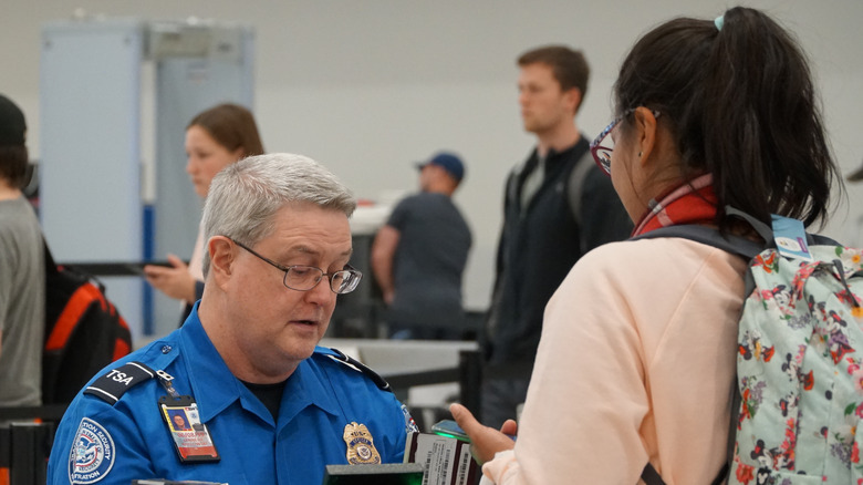 TSA worker checks passport at airport