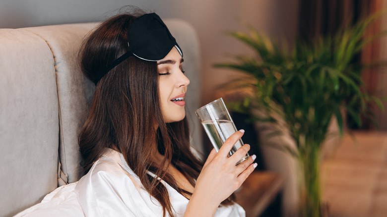 Woman drinks water in the bed