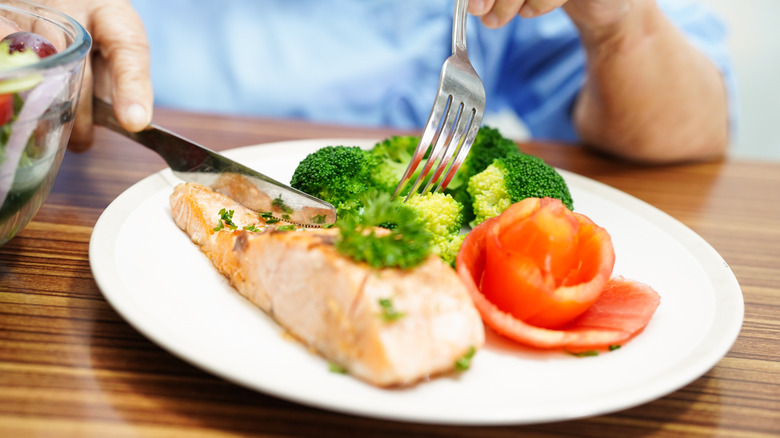 Man eating salmon with broccoli 