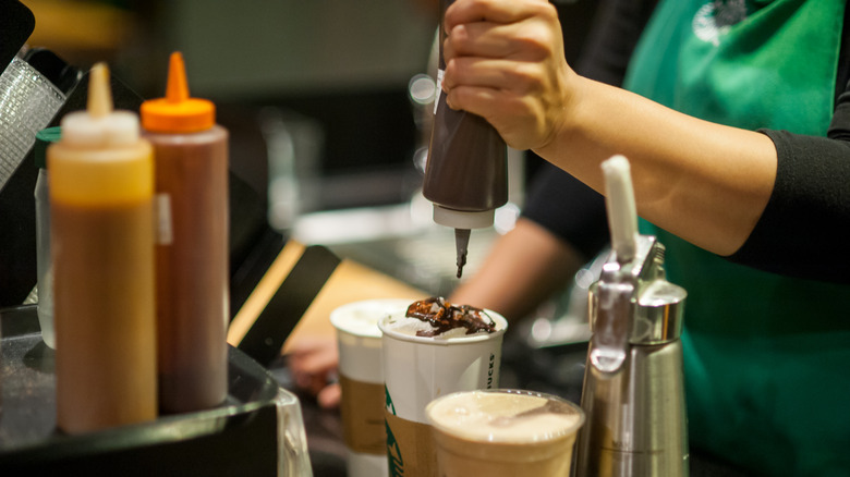 Starbucks worker putting syrup on top of drink