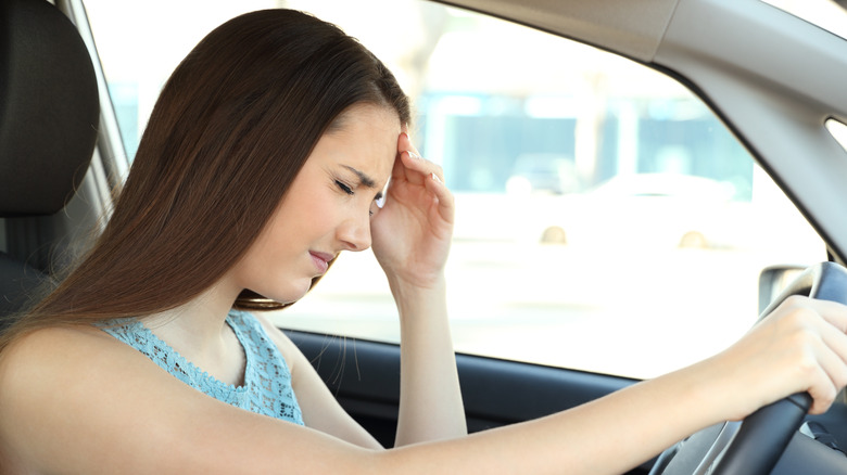 Side view portrait of a driver suffering migraine driving a car