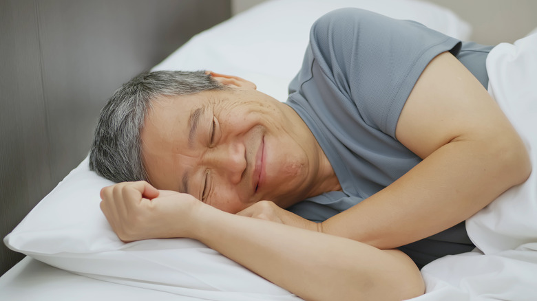 Smiling man sleeping on his side in bed