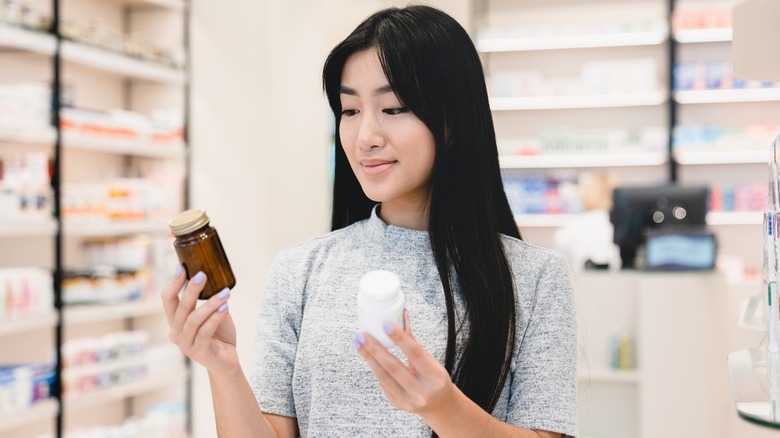 Woman comparing two bottles at pharmacy