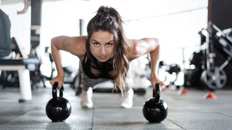 Woman doing push-ups on kettlebells