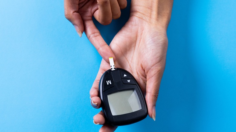 african american woman checking sugar using glucometer