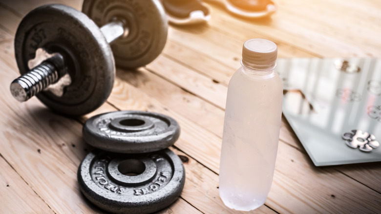 A bottle of water next to a set of dumbbells 