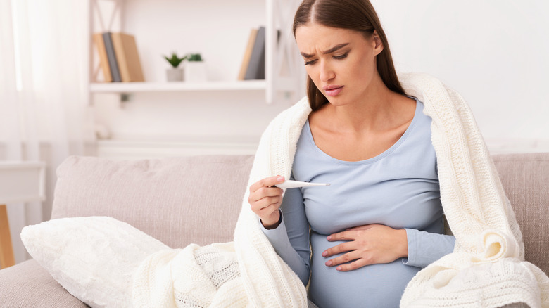 pregnant woman taking her temperature