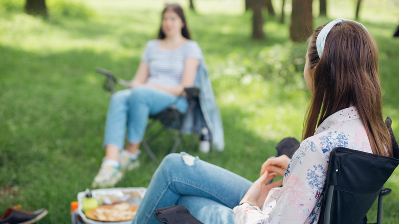 Two women sitting outside socially distanced