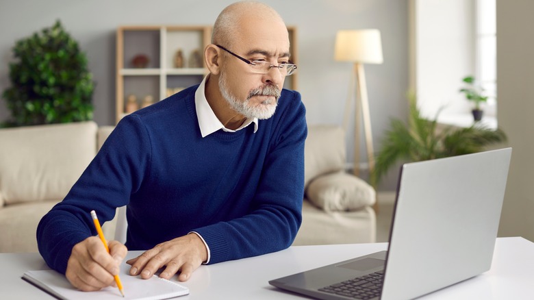 A man making notes from laptop