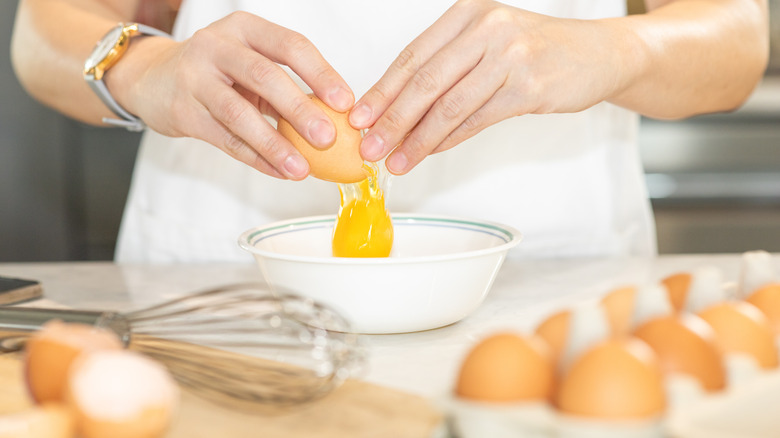 Hands cracking egg into bowl