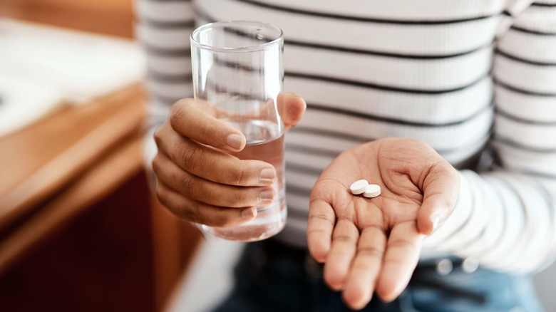 Hands holding pills and water