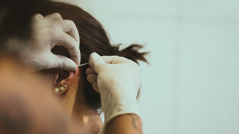 Close up of woman getting her ear pierced