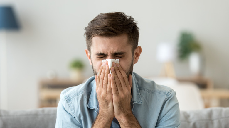 Man blowing his nose into tissue