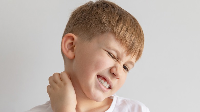 Boy scratching an itchy neck rash