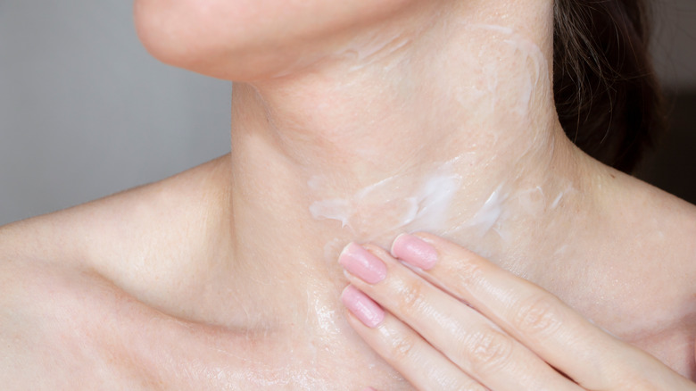 Woman rubbing cream on neck