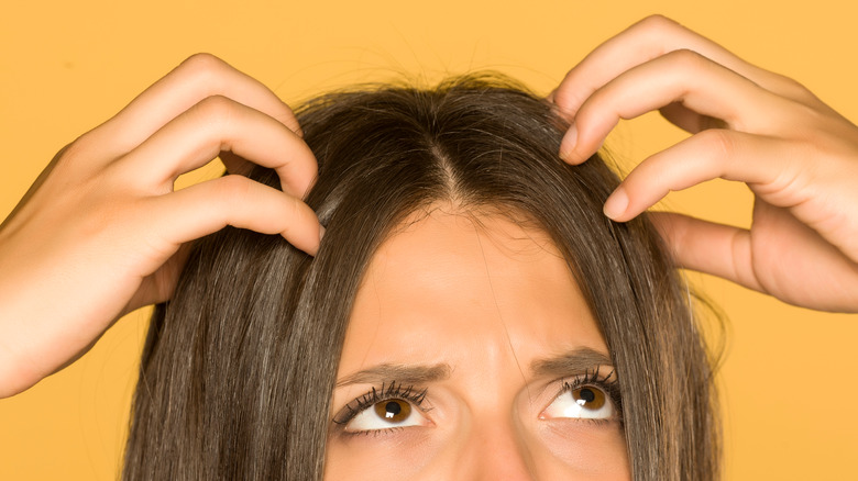 Woman scratching scalp with both hands