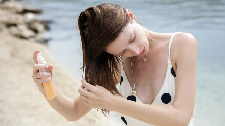 Woman at beach applying sunscreen spray