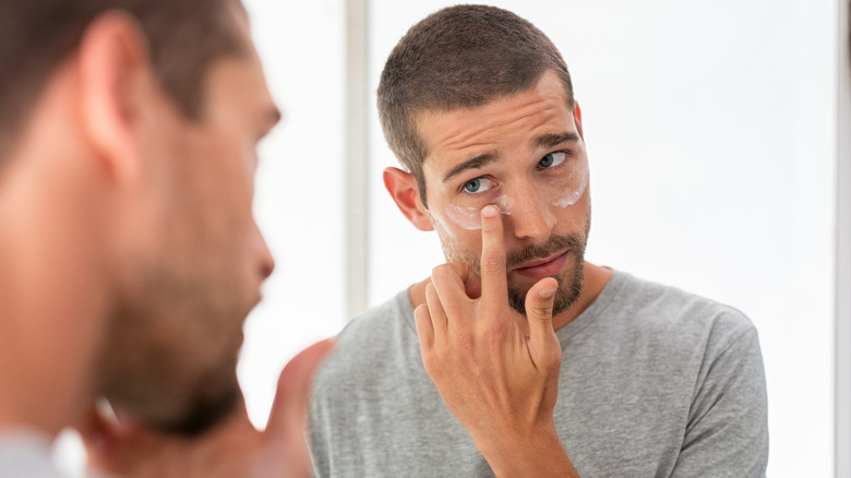 Man applying face cream in mirror