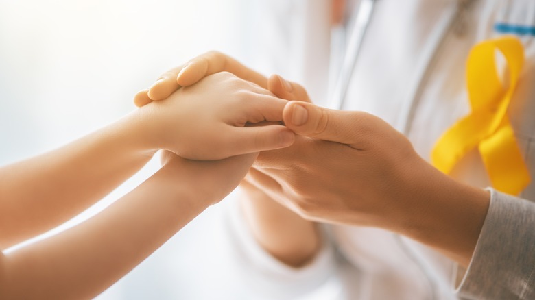 Cancer patient holding doctor's hands 